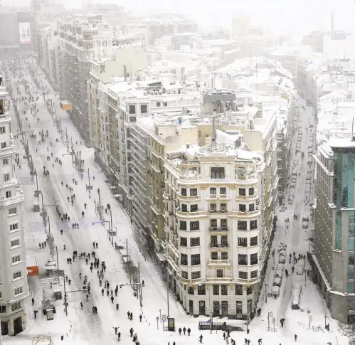  ??  ?? People walk during a heavy snowfall in downtown Madrid on Saturday. A persistent blizzard has blanketed large parts of Spain, halting traffic and leaving thousands trapped in cars or in train stations and airports that suspended all services.