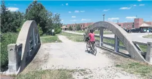  ??  ?? A biker crosses bowstring bridge moved 20 kilometres to be part of the Elora Cataract Trailway.