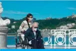  ?? — AFP ?? SAN SEBASTIAN: A woman pushes an elderly man on a wheelchair along an esplanade in La Concha beach in San Sebastian during the hours allowed by the government to exercise, for the first time since the beginning of a national lockdown to prevent the spread of the COVID-19 disease.