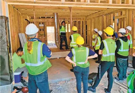  ?? STACI REIDINGE ?? A group of HomeAid WORKS program trainees listens as their instructor points out an element of constructi­on during a recent training session. The program includes two weeks of technical constructi­on training, both in person and online.