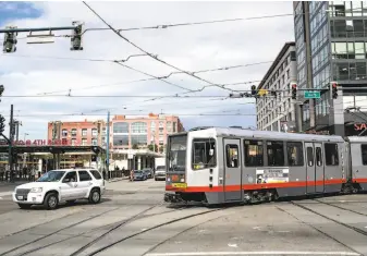  ?? Brian Feulner / Special to The Chronicle ?? A train along Muni’s T line encounters a familiar obstacle: a car attempting to make an illegal left turn at Fourth and King streets. Traffic is one of the factors that often slow down the line.