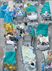  ?? ?? Patients lie on hospital beds as they wait at a temporary holding area outside a medical centre in Hong Kong on Wednesday.