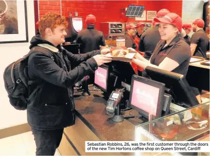  ??  ?? Sebastian Robbins, 26, was the first customer through the doors of the new Tim Hortons coffee shop on Queen Street, Cardiff