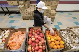  ?? Irfan Khan Los Angeles Times ?? AN L.A. UNIFIED cafeteria crew member makes food bags at James A. Garfield High School. The district wants to be reimbursed $100 million for meals for adults.