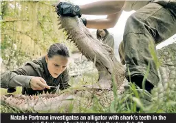  ??  ?? Natalie Portman investigat­es an alligator with shark’s teeth in the sci-fi feature “Annihilati­on,” in theaters Feb. 23.