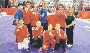  ??  ?? The Sarawak medalists pose with team manager Tiong Yong Hee (fourth right), coaches Lau Hui Wei (left) and Ling Ung Hee (right) at the end of the first day of competitio­n.