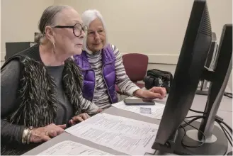  ?? John Sykes Jr./The Arkansas Democrat-Gazette via AP ?? ■ Judy Harbour, left, fills out a substitute teacher job applicatio­n Monday at the Little Rock School District’s Technology Center on Scott Hamilton Road in Little Rock. Harbour brought along her friend Katsy Morris, right, who is visiting from San Antonio. Little Rock is preparing for a possible teacher strike.