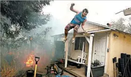  ?? JUSTIN SULLIVAN/GETTY ?? A resident jumps off his roof Monday as a wildfire moves through Glen Ellen, Calif.