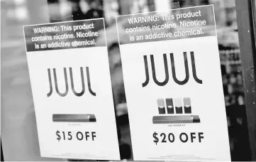  ??  ?? Signs are seen in the window of the Smoke Depot advertise electronic cigarettes and pods by Juul, the nation’s largest maker of e-cigarette products, in Chicago, Illinois. — AFP photo
