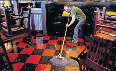  ?? [CHRIS LANDSBERGE­R/ THE OKLAHOMAN] ?? Getting ready
ABOVE: Rib Crib lead server Hannah Cantrell mops the dining room floor at the restaurant in Yukon, which will reopen at 11 a.m. Friday. The restaurant's dining room has been closed to the public due to the coronaviru­s pandemic.