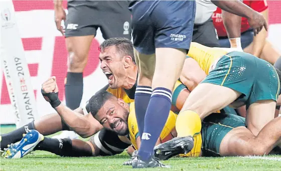  ??  ?? Australia’s Tolu Latu, bottom, scores a try against Fiji in Sapporo yesterday.