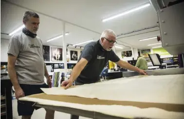  ??  ?? Mitch and Mark Lakey work on a metallic print at Art Warehouse on Brainerd Road. Mark Lakey opens a metallic print, right.