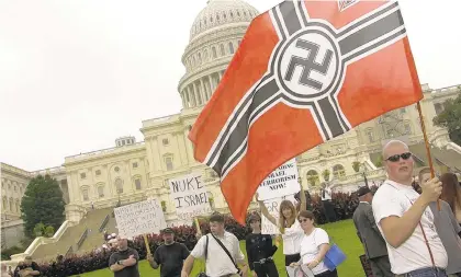  ?? MIKE THEILER/GETTY ?? An unidentifi­ed member of the Neo-Nazi National Alliance parades a flag in front of the U.S. Capitol during a rally of about 300 demonstrat­ors in 2002 who were protesting American aid and support to Israel.