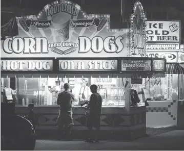  ?? SCOTT OLSON / GETTY IMAGES ?? Fairgoers hit the corn dog stand at the Iowa State Fair this week in Des Moines. The event is expected to draw one million people. Fairs seem to appeal to the yearning for something familiar, for simpler times.
