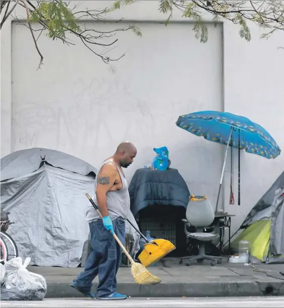  ?? Photograph­s by Francine Orr Los Angeles Times ?? DUANNE HARDAWAY, 44, known on the streets as X — as in extra large, 6 feet 3 and 368 pounds — cleans up his area of the homeless encampment where he lives on Broadway Place in South Los Angeles. X had been homeless most of his life, starting when his father threw him out as a teen. At first, he squatted in abandoned buildings.