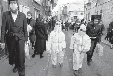  ?? MENAHEM KAHANA/GETTY-AFP ?? Protected during Purim: Ultra-Orthodox Jewish children dressed in hazmat suits celebrate Purim on Sunday in Jerusalem. Coronaviru­s restrictio­ns in Israel failed to prevent street parties and prayer celebratio­ns in ultra-Orthodox areas, which have repeatedly flouted safety rules. Purim marks the victory of Jews over a tyrant in ancient Persia.