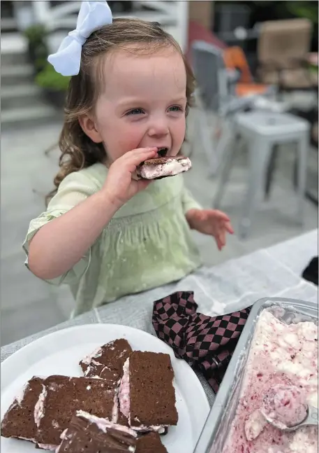  ?? TNS ?? CHILD APPROVED: Greta McKay, 2, enjoys a homemade ice cream sandwich filled with no-churn strawberry ice cream.