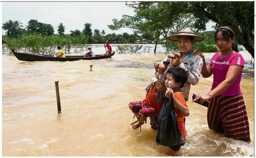  ??  ?? To safer ground: Residents making their way in floodwater­s in Shwegyin, Bago region. Fears that embankment­s could burst under fresh rains mounted in flooded southeaste­rn Myanmar, where more than 150,000 people have been forced to flee. — AFP