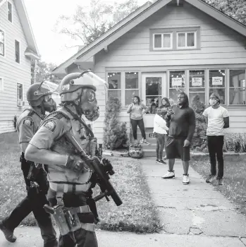  ?? JOHN MINCHILLO/AP ?? Police patrol a street May 28, 2020, in St. Paul, Minnesota, as protests flared over George Floyd’s death.