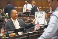  ??  ?? State Rep. Craig Fishbein, R-Wallingfor­d, holds up a sign after a vote on the final day of session Wednesday.