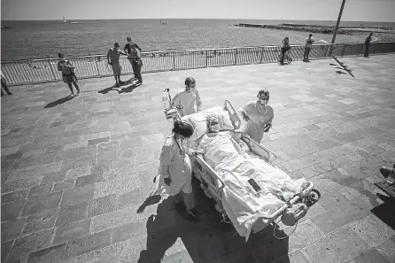  ?? Emilio Morenatti, The Associated Press ?? Medical workers return patient Francisco España, 60, to a hospital after spending a few minutes at the promenade in Barcelona, Spain, on Friday. The hospital is studying how short trips to the beach may help COVID-19 patients recover from long and traumatic care in hospital ICU wards.