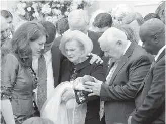  ??  ?? A 2012 photo provided by a former member of the church shows Word of Faith Fellowship leader Jane Whaley, centre, holding a baby, accompanie­d by her husband, Sam, centre right, during a ceremony at the church's compound in Spindale, North Carolina.