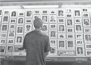  ?? JEFF SWENSEN, GETTY IMAGES ?? A visitor looks through the portraits of Sept. 11 victims at the Flight 93 National Memorial in Shanksvill­e, Pa. Nearby, the Sacred Ground plaza marks the point of the jet’s impact in 2001.