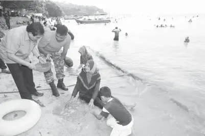  ??  ?? HILMI (kiri) melihat jenis siput yang dicari oleh peserta selepas merasmikan pertanding­an ‘Jom Cari Siput’ di Pantai Gertak Sanggul, Teluk Kumbar yang dianjurkan oleh Parlimen Balik Pulau, kelmarin. -Gambar Bernama