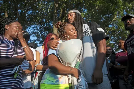  ?? Jessie Wardarski/ Post- Gazette ?? Rodshenna Hawkins of Chartiers City, left, aunt of Jordan Duckett, wipes away tears as Jordan’s mother, Laken Duckett, of Chartiers City, hugs one of her son’s football coaches, Mike Harper, of Sheraden, during a gathering Thursday at Chartiers Park in Chartiers City. Jordan, 13, a firstyear football player with the Mustangs, died Wednesday after collapsing on the field during practice. Video at post- gazette. com.