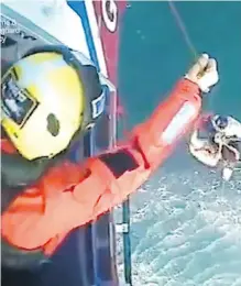  ??  ?? This image taken from a video shows surfer Matthew Bryce being plucked from the sea off the western coast of Scotland on Monday.