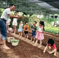  ??  ?? Children from the city of Xiamen learn farming techniques from a villager in Yuanqiansh­e.