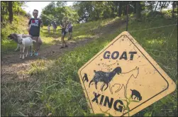  ??  ?? Hikers walk past a “goat crossing” sign.