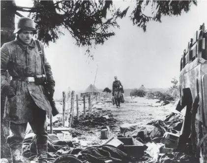  ?? AP ?? During the German counteroff­ensive in the Ardennes region, known as the Battle of the Bulge, a German soldier looks through American ration boxes and uniforms on Jan. 3, 1945, somewhere in the Belgium-Luxembourg salient.