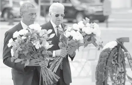  ?? JOE BURBANK/ORLANDO SENTINEL ?? President Barack Obama and Vice President Joe Biden place flowers during a 2016 visit to the makeshift memorial at the Dr. Phillips Center for the Performing Arts, honoring those killed in the Pulse club massacre, in downtown Orlando.