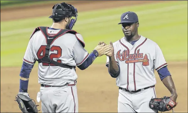  ?? ALAN DIAZ / ASSOCIATED PRESS ?? Closer Arodys Vizcaino is congratula­ted by catcher Tyler Flowers after the Braves earned their first win of the season Friday against the Marlins in Miami. Vizcaino worked out of jams in the eighth and ninth innings.