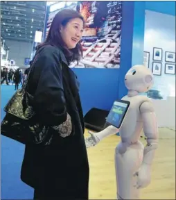  ?? FENG YONGBIN / CHINA DAILY ?? A visitor communicat­es with a robot at British bank Standard Chartered’s booth at the China Internatio­nal Import Expo on Thursday.