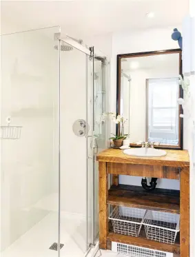  ??  ?? Le meuble-lavabo, fait de planches de bois brut, renforce le look rustique chic de cette petite pièce dans laquelle une douche vitrée parvient à se tailler une belle place.