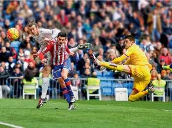  ?? — AP ?? Real Madrid’s Gareth Bale ( left) scores the opening goal against Sporting Gijon in their Spanish League match at Santiago Bernabeu in Madrid on Sunday. Real won 5- 1.