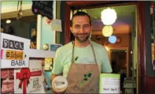  ?? MICHILEA PATTERSON — DIGITAL FIRST MEDIA ?? Ashraf Khalil, owner of the all-vegan iCreate Café in Pottstown, poses for a photo with a container of hummus and a canister he’s using to collect money for families that need help purchasing school supplies. His “Hummus for Houston” fundraiser will...