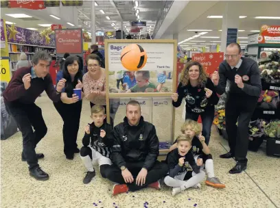  ??  ?? Charles Champion; Lynn Young, Tesco people manager; Nikki Edwards, Tesco community champion; Tondu FC players; Laura Thomas; and Gareth Jeffries, Tesco GM Manager, celebrate the award of thousands of pounds to Bridgend community groups