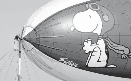  ?? Casey Christie / Bakersfiel­d California­n file ?? Mike Carr, part of the ground crew for the MetLife blimp, works on the helium-filled airship at the Bakersfiel­d, Calif., Municipal Airport in 2008. MetLife announced Thursday it will stop its use of Snoopy and other “Peanuts” characters.
