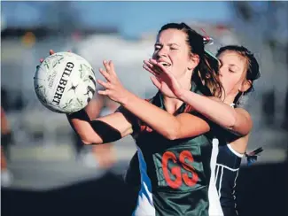  ?? Photo: NATASHA MARTIN ?? Reaching out: Mackenzie College Old Girls’ Laura Gibson fends off a challenge from Timaru Girls’ High’s Jess Golding during her side’s 41-18 win at the SBS netball courts on Saturday.