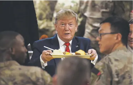  ?? Olivier Douliery, AFP/Getty Images ?? President Donald Trump serves Thanksgivi­ng dinner to U.S. troops at Bagram Air Field during a surprise visit Thursday in Afghanista­n. About 12,000 American forces remain in the country.