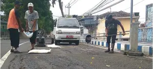  ?? SIGIT HARIYADI/JAWA POS RADAR BANYUWANGI ?? WILAYAH: Tiga personel satgas jalan berlubang bekerja menambal lubang di Jalan Dr Soetomo, Banyuwangi.