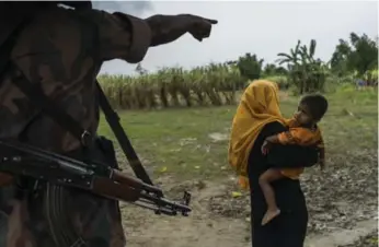  ?? ADAM DEAN/THE NEW YORK TIMES ?? A border guard sends a Rohingya woman back to her camp along the border of Burma near Gundum, Bangladesh.