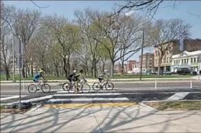  ?? Pam Panchak/Post-Gazette ?? Bicyclists pedal along the new bike lanes and across the new pedestrian crossing on Federal Street through the Allegheny Commons on Wednesday.