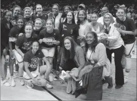  ?? JESSICA HILL, THE ASSOCIATED PRESS ?? Former and current Connecticu­t basketball players gather for a team photograph -- that’s Hamilton’s Kia Nurse, centre holding a bill -- after winning their 100th consecutiv­e game Monday.