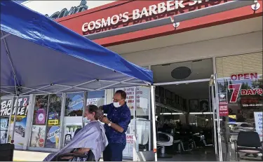  ?? ASSOCIATED PRESS FILE PHOTO ?? A customer of Cosmo’s barber shop receives a haircut in the parking lot in front of the shop in July in Pleasanton, Calif. The coronaviru­s and the drastic measures put in place by government officials to try to control its spread had a severe toll on many small businesses in the U.S. Restaurant­s, hair salons, event planners and other businesses that rely on people being in close proximity were particular­ly hard-hit, as were those tied to tourism.