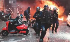  ?? AFP ?? Riot police next to a car set on fire during the ‘yellow vest’ protest on the Champs-Elysees avenue in Paris.