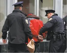  ?? Paul Chinn / The Chronicle ?? Police search a man who was taken into custody at Grove and Market streets, where more officers are walking the beat.